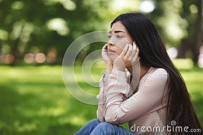 Solitude. Upset Girl Sitting On Lawn In Park And Thinking About Something Stock Photo