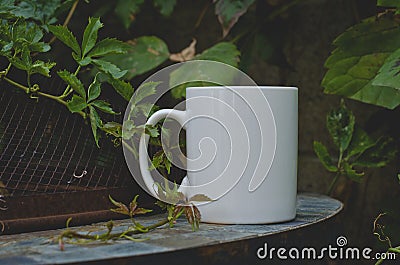 A solo blank white coffee mug on the vine covered fire pit Stock Photo