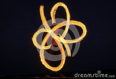 Solo fire artist perform infinite spirals by spinning flaming pois on dark sky at night outdoors, blaze Stock Photo