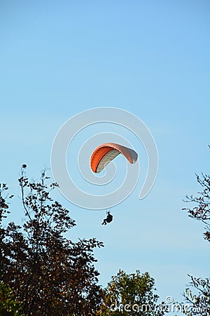 Solo paraglider is flying against the sun on a blue sky on a sunny day in Hungary Stock Photo