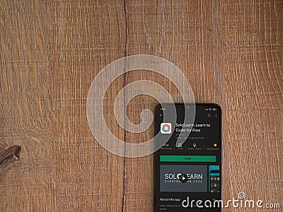 SoloLearn - Learning coding app play store page on the display of a black mobile smartphone on wooden background Editorial Stock Photo