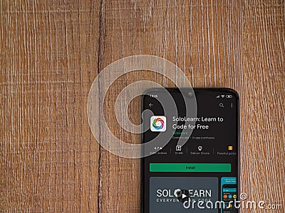 SoloLearn - Learning coding app play store page on the display of a black mobile smartphone on wooden background Editorial Stock Photo