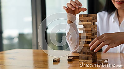 Solutions and Strategies Businesswoman placing or pulling wooden blocks on the tower business planning ideas risk management Stock Photo