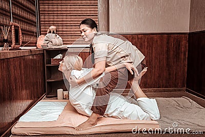 Masseuse helping her client straightening her back. Stock Photo
