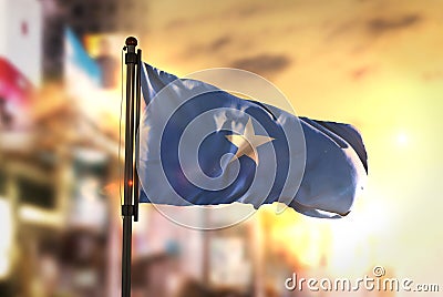 Somalia Flag Against City Blurred Background At Sunrise Backlight Stock Photo