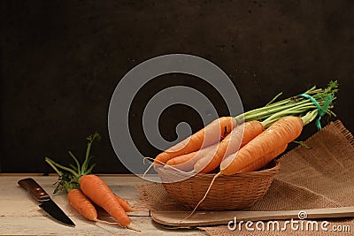 Some carrots on a wooden table of a rustic kitchen against a chalk black background. Stock Photo