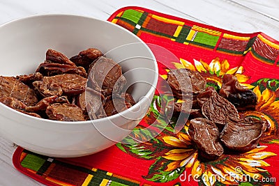 Some dehydrated beef testes for dogs in white bowl and vibrant clothes. Stock Photo