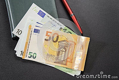 Some Euro banknotes with pen and notepad on dark Stock Photo