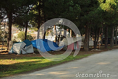 Some homeless tents in forest near road. Sad situation of America Stock Photo