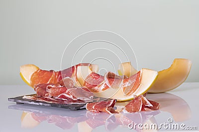 Melon slices with thin cured ham on a dark plate on a table Stock Photo