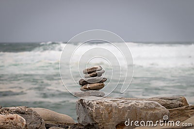 some rocks are stacked together on some logs by the ocean Stock Photo