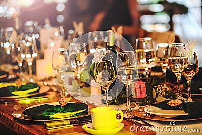 Some wine glasses, plates, forks and green briefcases for event celebration. Beautiful dinner table setting. Vintage decoration of Stock Photo