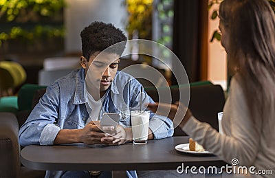 Bored black guy looking at smartphone during date time Stock Photo