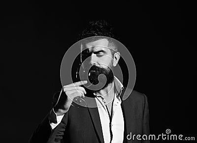 Sommelier with beard on emerald background. Connoisseur with serious face tasting expensive cabernet wine Stock Photo