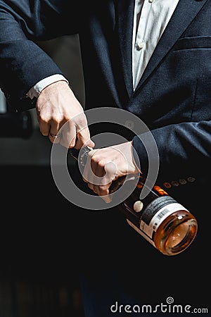 Sommelier in a dark blue jacket opens a bottle of rose wine Stock Photo