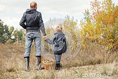 Son and father with full basket of mushrooms on the forest glade Stock Photo