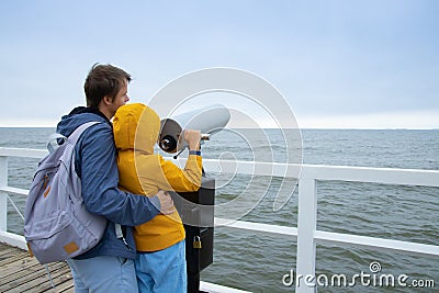 son and father look through coin binoculars at the cold sea. Stock Photo