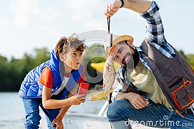 Son feeling surprised while seeing fish caught by father Stock Photo