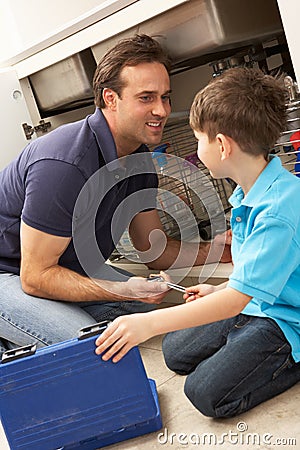 Son Helping Father To Mend Sink Stock Photo