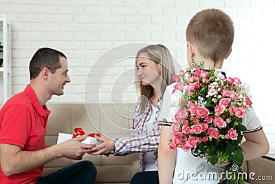 Son hiding bouquet to surprise mommy on mother`s day. Woman, man Stock Photo