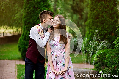 Son kisses, hugs his mom in summer day, outdoors. Young mother and her adult child having fun together. Mothers Day concept. Stock Photo