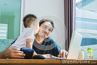 Son kissing his father while using internet. People and Lifestyles concept. Technology and Happy family theme. Single dad theme Stock Photo
