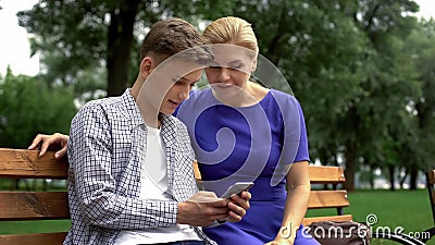 Son teaching mother to use application on smartphone, new technologies, gadget Stock Photo