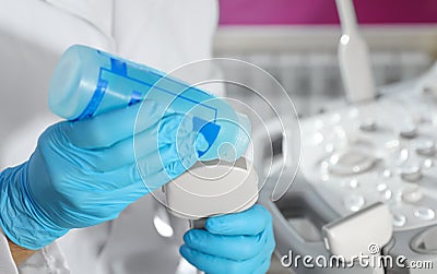 Sonographer covering ultrasound machine probe with gel Stock Photo