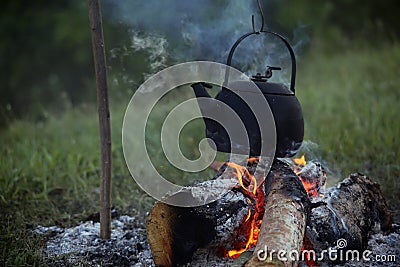 Sooty teapot boils and streaming on the bonfire Stock Photo