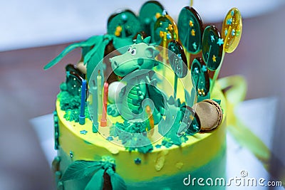 Sophisticatedly designed homemade Birthday cake with Dinosaur figure between the sweeties, green and yellow colors. Editorial Stock Photo