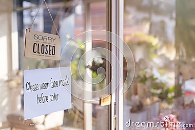 Sorry we are closed wood sign and Please wear face mask befor enter paper on glass door Protection to pandemic of coronavirus. Stock Photo