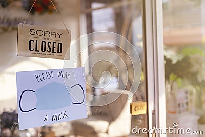 Sorry we are closed wood sign and Please wear face mask befor enter paper on glass door Protection to pandemic of coronavirus. Stock Photo