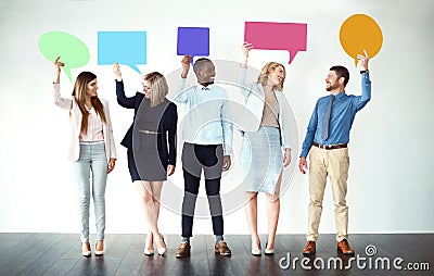 Sorry what did you say. Shot of a group of work colleagues standing next to each other while holding speech bubbles Stock Photo