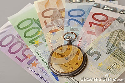 Pile of sorted banknotes with old vintage watch on them Stock Photo