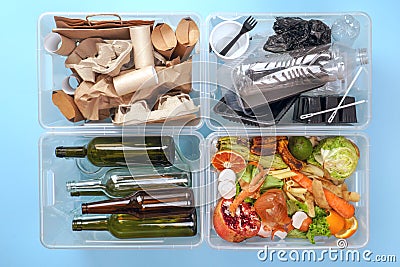 Sorting garbage. Four transparent containers with trash on a blue background: glass, plastic, organic trash, paper Stock Photo