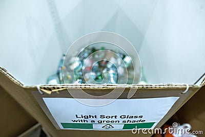 Sorting recyclables. The sorted clear with a green shade glass bottles, is placed in a container with the appropriate marking Stock Photo