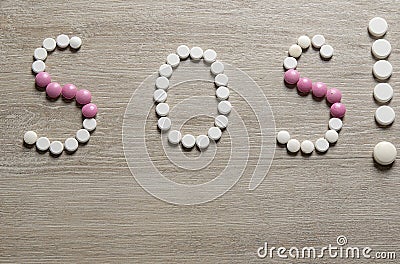 SOS word made of pills on a wooden table. Different pills and blister packs Stock Photo