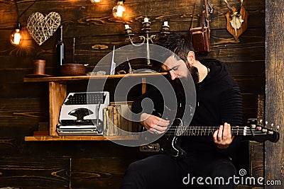 Soul music. Man bearded musician enjoy evening with bass guitar, wooden background. Man with beard holds black electric Stock Photo