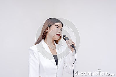 A soulful young woman holding a microphone towards her mouth while facing sideways to the right. Isolated on a white background Stock Photo
