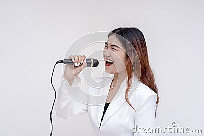 A soulful young woman singing into a microphone while facing sideways. Isolated on a white background Stock Photo