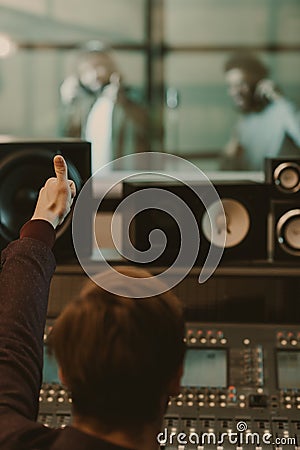 sound producer showing thumb up to singers behind glass Stock Photo