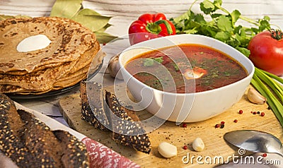 Soup, a plate of borscht with greens and sour cream, bread, pancakes, vegetables Stock Photo