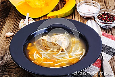 Soup with chicken, pumpkin and noodles on wooden table Stock Photo