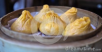 soup dumplings in a bamboo steam tray on wooden table (Xiaolongbao, xiao long bao) pork, colorful dough Shanghai Stock Photo