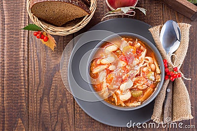 Soup with turkey, pasta, carrot, celery, tomato and cannellini beans, garnished with parmesan cheese, on the table with autumn Stock Photo