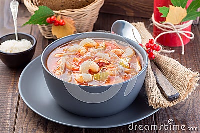 Soup with turkey, pasta, carrot, celery, tomato and cannellini beans, garnished with parmesan cheese, on the table with autumn Stock Photo