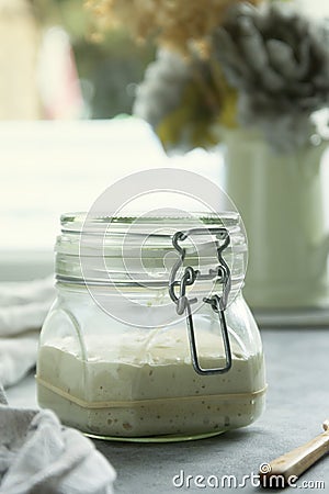 Sourdough starter in a jar, yeast-free leaven starter for healthy organic rustic bread, home baking concept Stock Photo