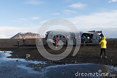 South Iceland 03 March 2018 : Tourist walking to famous landmark the abandoned wreck of a US military plane on Solheimasandur Editorial Stock Photo