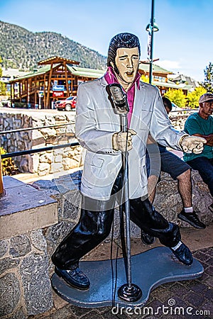 Statue of Elvis singing with microphone and blue suede shoes on sidewilk in South Tahoe with tourist Editorial Stock Photo