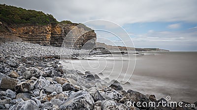 South Wales coastline, showing the water lapping against the rocky shore, flanked by high cliff. Stock Photo